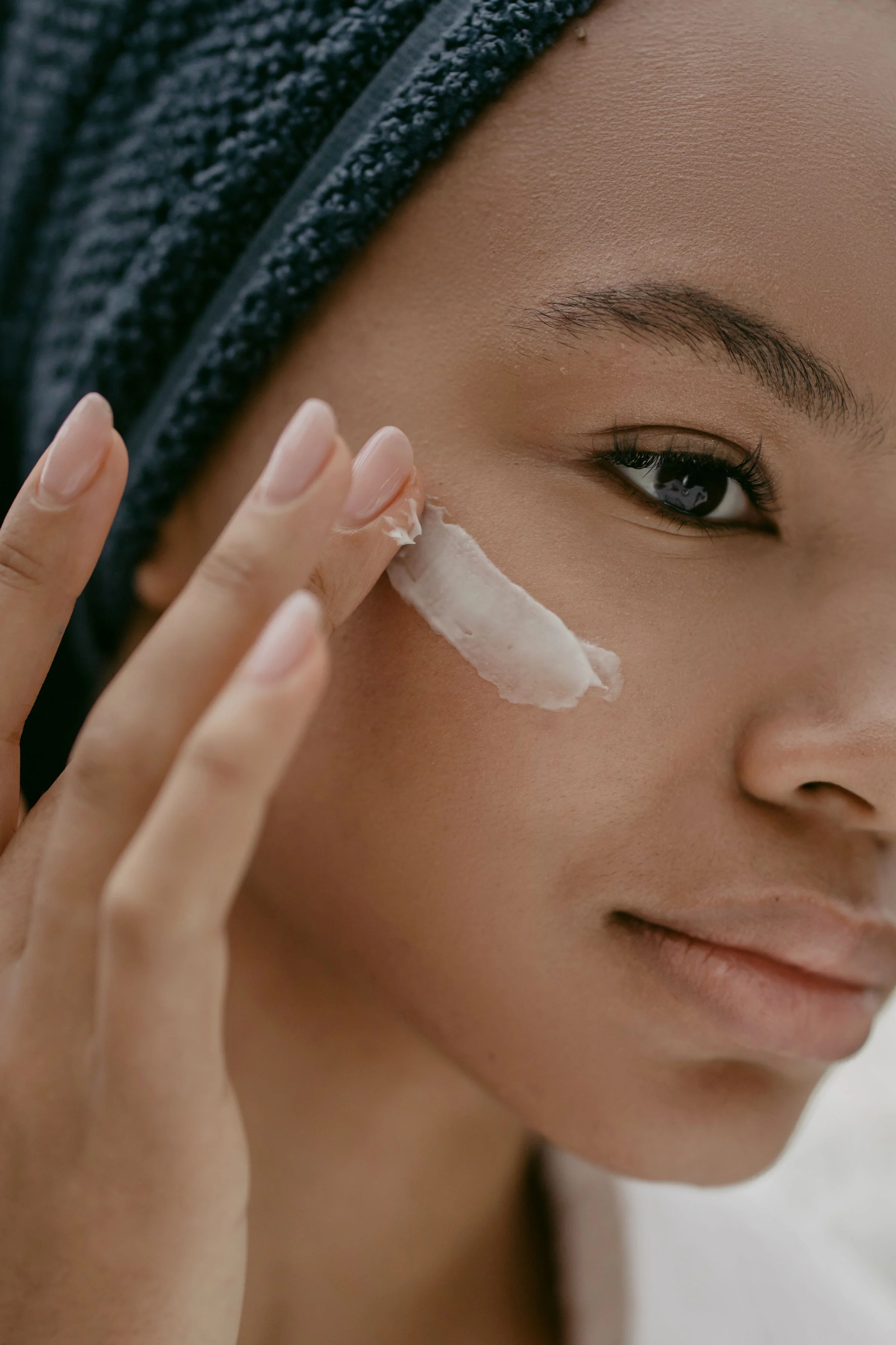 Fingertips pressing a cream product into the cheek Fingertips pressing a cream product into the cheek